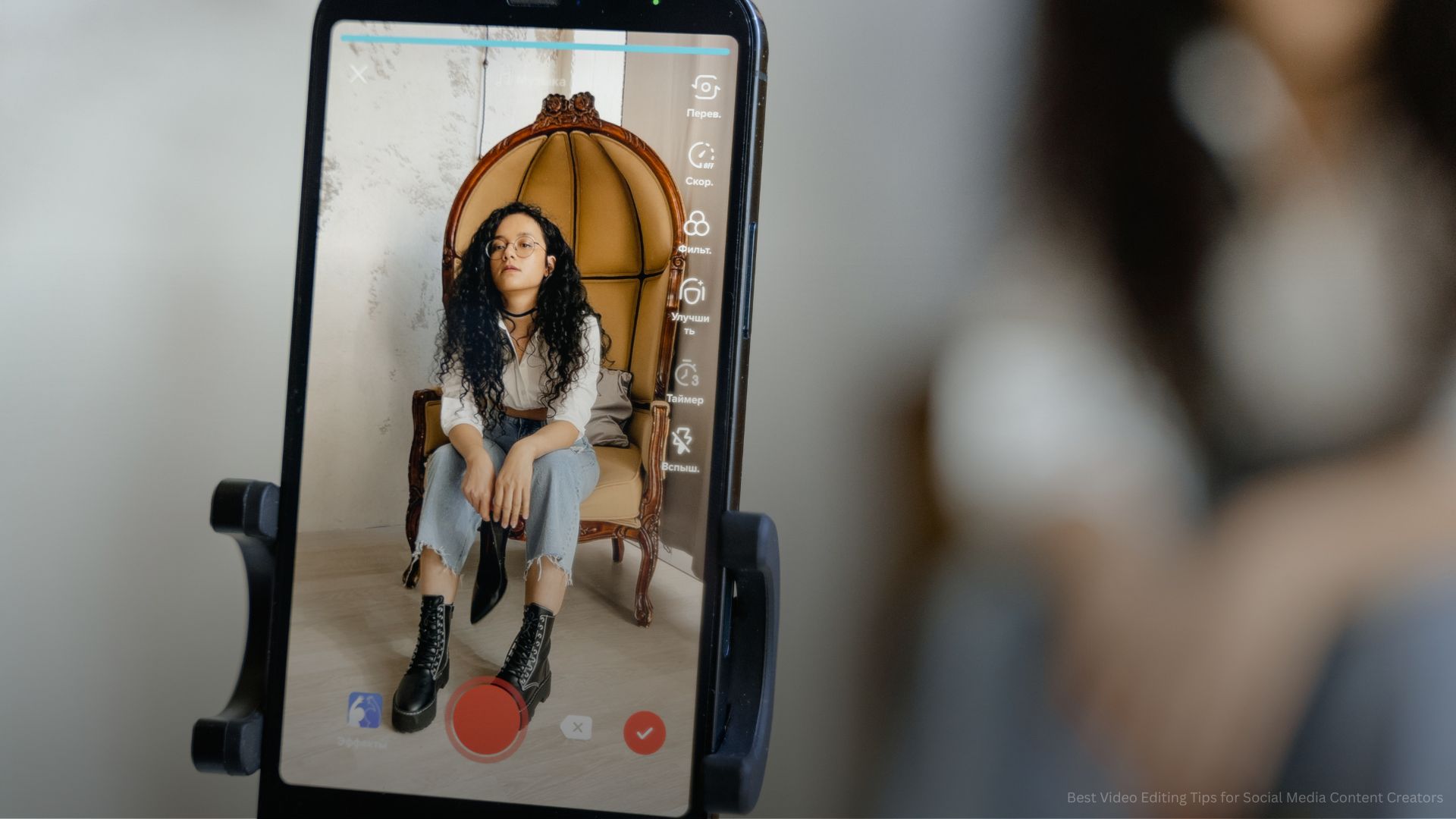 A Close-Up Shot of a Smartphone Recording a Woman Sitting on a Chair